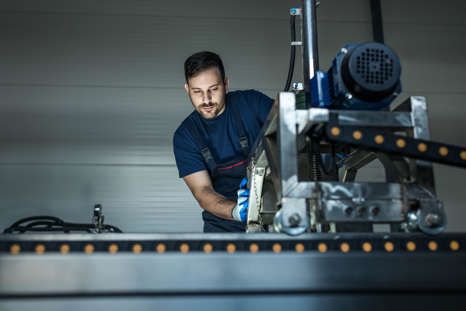 Blue collar worker working on a production line machine in a factory.